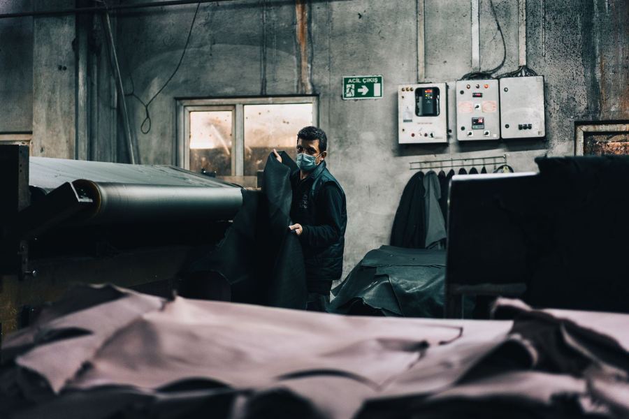 Operator working at a running conveyor belt line inside a processing plant