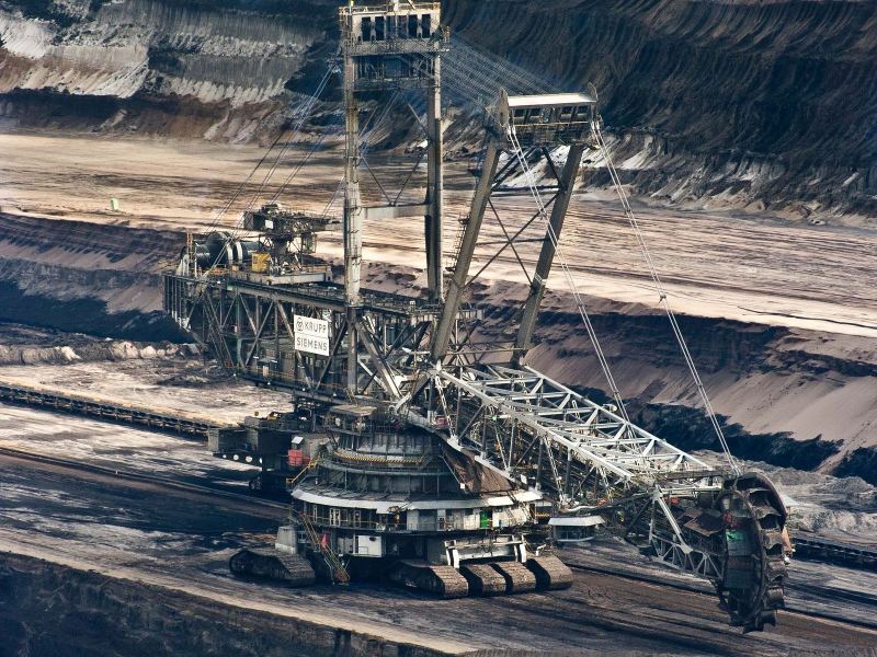 Bucket-wheel excavator working an open-pit mining bench beside overland conveyors